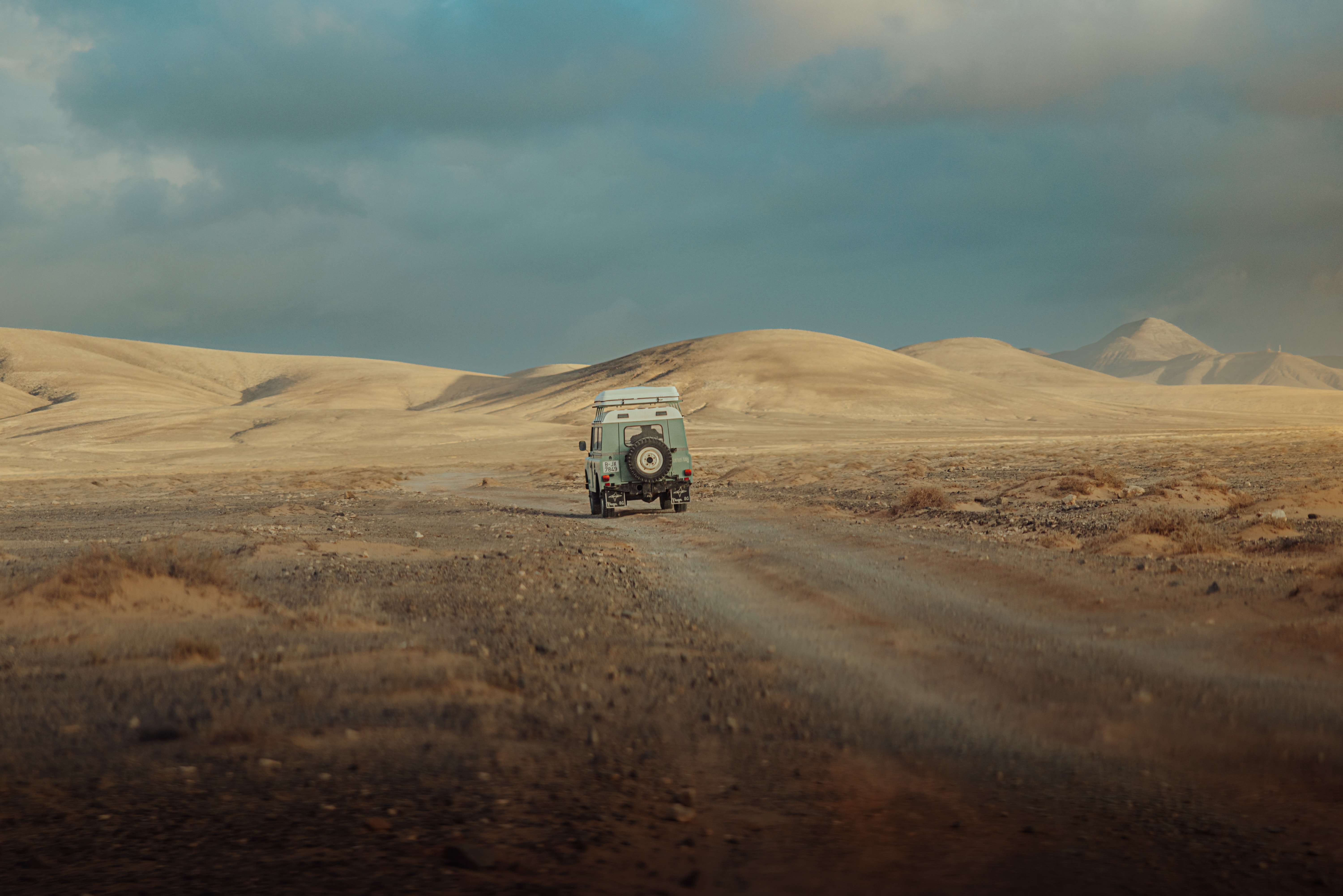 baby blue car driving through desert dunes